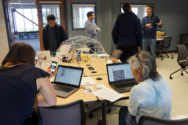 Mehrere Personen unterhalten sich und arbeiten an Laptops in einem Maker Space.