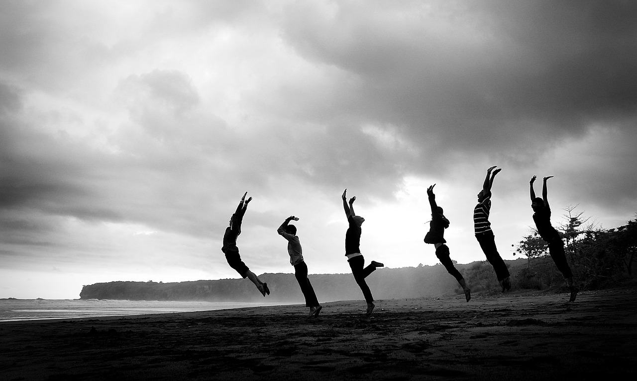 Das Bild zeigt Menschen die am Strand hochspringen.