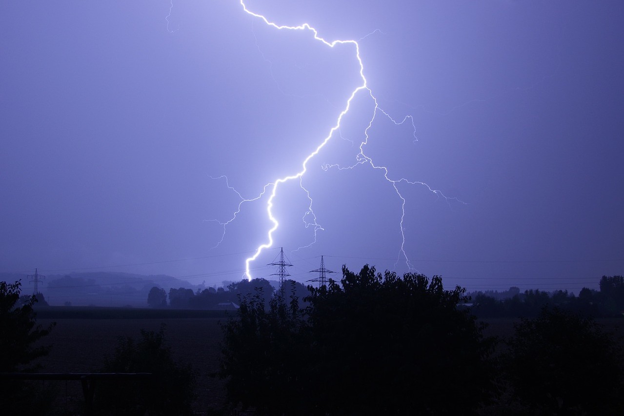 Landschaft im Dämmerlicht, ein Blitz zuckt über den Himmel