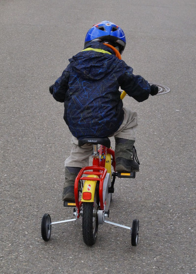 Ein Kind fährt auf einem Fahrrad mit Stützrädern